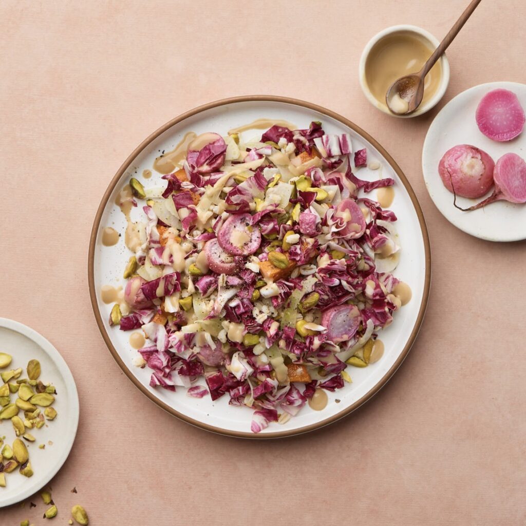 roasted radish and squash salad with nuts and a vinaigrette on a ceramic plate